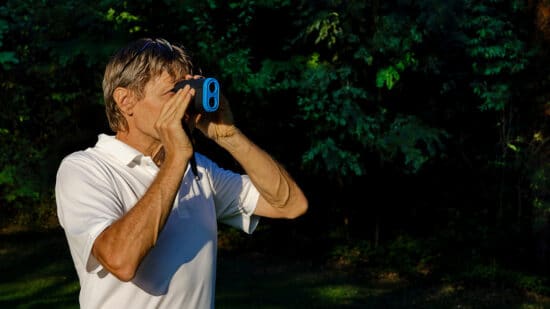 Un golfeur mesure la distance à jouer avec son télémètre de golf